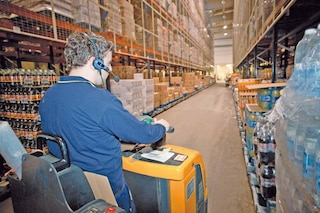 An operator prepares orders in boxes, aided by a voice picking system